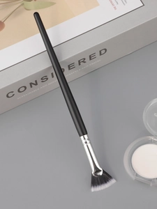 Detail of fan makeup brush with white-tipped bristles for highlighting and setting powder
