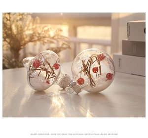 Palla di Natale trasparente con bacche rosse e neve finta in una calda luce naturale