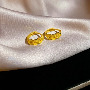 Close-up of 18k gold plated hoop earrings with coin pattern on pink silk fabric
