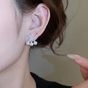 Eleganti orecchini a stella in zircone con tre perle bianche pendenti su modella