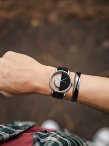 Detail view of the TOMI watch and leather bracelet set on a wrist with nature background