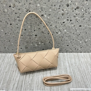 Detail of beige woven genuine leather handbag with knot strap on terrazzo surface