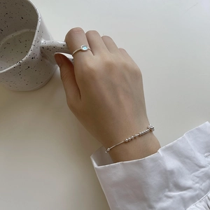 Close-up of S925 sterling silver beaded bracelet and oval moonstone ring on model's hand