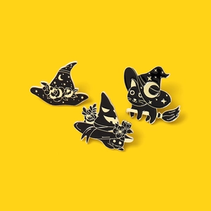 Three-piece Halloween enamel pin set with black cat and witch hat on yellow background