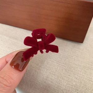 Close-up of burgundy velvet bow hair clip showing soft flocking texture and small size