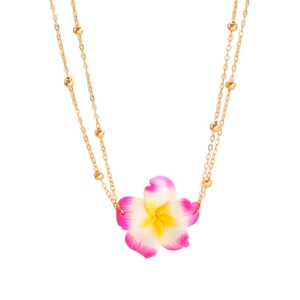 Detail van roze frangipani bloem hanger aan een gouden kralenketting voor het strand