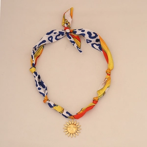 Detail of blue leopard print silk scarf necklace with golden sun face pendant