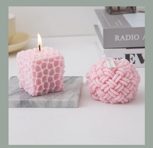 Cozy pink honeycomb and knot scented candles with warm flame on marble coaster