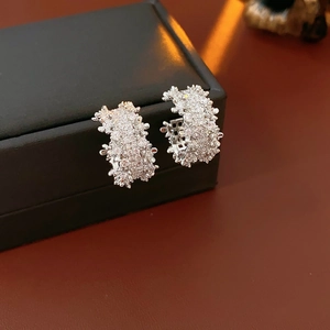 Macro side view of silver C-shaped earrings with zircon pavé on jewelry box