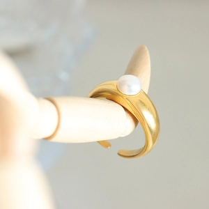 French style gold open ring with large freshwater pearl on a wooden hand stand