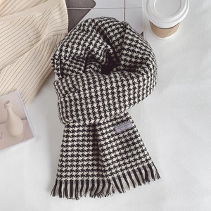 Detailed texture of black and white houndstooth wool blend scarf with fringe edges