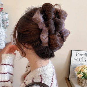 Detail of plush bow claw clip in purple and brown faux fur worn on hair for winter