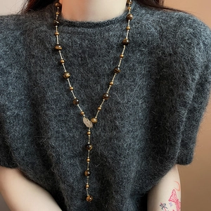 Close-up of vintage long Y-necklace with tiger eye beads and zircon leaf charm