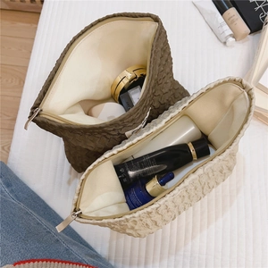 Détail de trousses à maquillage matelassées marron et blanc cassé avec fermeture éclair