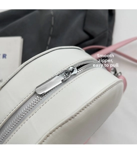 Detailed close-up of smooth silver metal zipper and hardware on white leather crossbody bag