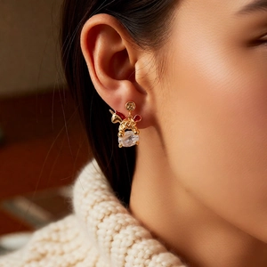 Close-up of 18k gold plated horse pendant earrings with red accents and zircon details