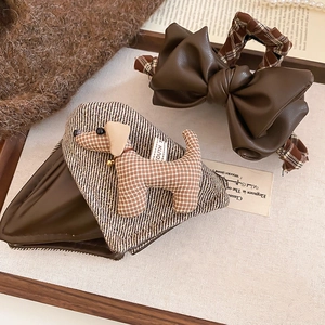 Detail of dog plush hair clip and dark brown leather bow hair clip on cozy background
