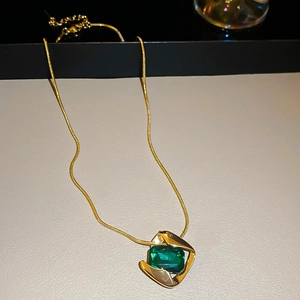 Detail showing a vintage gold snake chain with a square green gemstone pendant