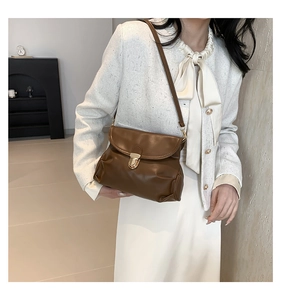 Brown soft leather pleated shoulder bag with gold metal clasp on white dress model