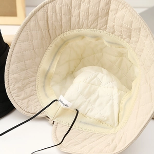 Detail view of beige quilted fisherman hat lining with adjustable drawstring and label