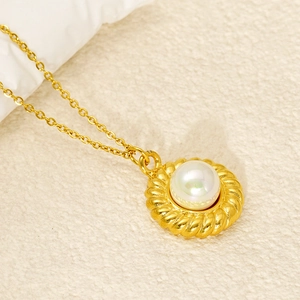 Gros plan d'un collier de perles dorées avec pendentif cercle torsadé sur tissu beige