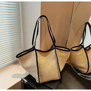 Detail of a large straw tote bag with black trim reflected in an elegant oval mirror
