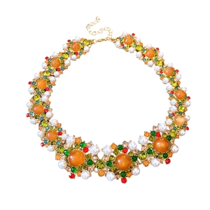 Collier vintage doré avec perles d'ambre, strass et perles sur fond blanc pur