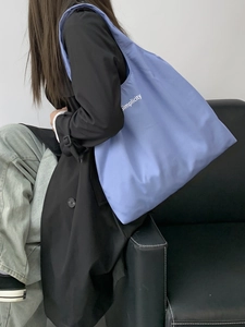 Large blue canvas tote bag with simplicity text shown on a model in a minimal setting