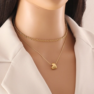 Gold double-layered necklace featuring a heart pendant and snake chain on a model