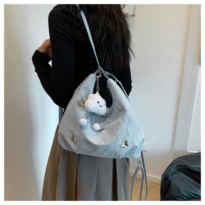 Detail of light blue pleated crescent shoulder bag with butterfly charm and cloud pendant