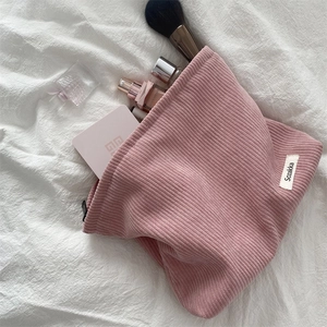 Pink corduroy makeup bag with zipper closure and spacious interior on a white fabric