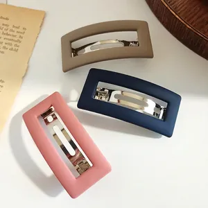 Set of three matte rectangular hair clips in pink, navy, and khaki on a white background