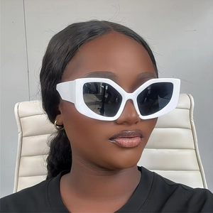 Close-up of white cat-eye sunglasses with dark grey lenses worn by a fashion model