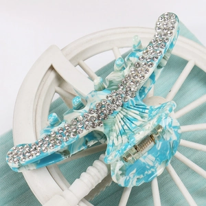 Detail of blue marble acetate hair claw clip with triple-row rhinestone embellishments