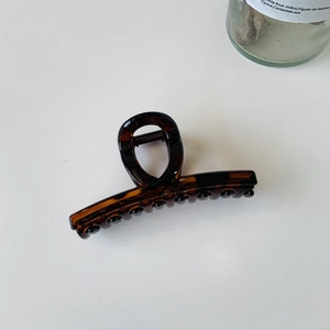 Détail macro d'une pince à cheveux en écaille avec ressort métallique sur fond blanc