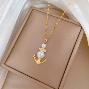 Dettaglio della collana ancora dorata con perle bianche e cristalli brillanti