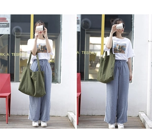 Street style shot of a green canvas tote bag paired with a casual outfit and white sneakers