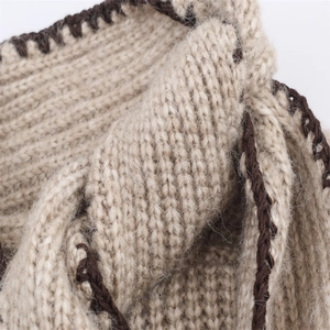 Vue macro d'un tricot côtelé beige avec des coutures décoratives marron foncé sur les bords