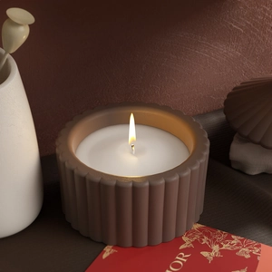 Gros plan d'une bougie allumée dans un pot en céramique nervuré brun au ton chaleureux