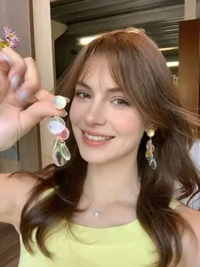 Detail of layered colorful translucent disc drop earrings on model with pearl necklace