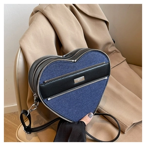 Close-up of heart-shaped crossbody bag featuring blue denim and black leather patchwork