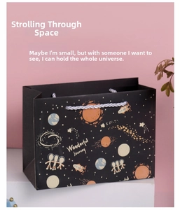 Detail der schwarzen Geschenktüte mit Weltraummotiv und silbernem Kordelgriff