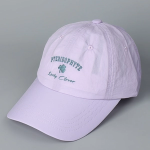 Detail of lavender quick-dry baseball cap featuring clover embroidery and lettering