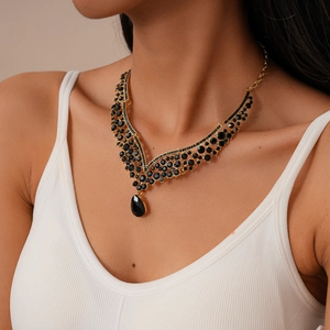 Detailed view of vintage gold V-shaped necklace featuring black crystals and teardrop pendant