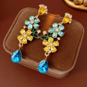 Detailed close-up of vintage floral tassel earrings with colorful crystals on velvet