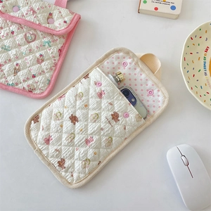 Detailed macro view of quilted cotton phone pouch with snap closure and animal prints