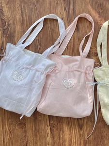 Pastel canvas drawstring tote bags in white, pink, and yellow with lace heart patches