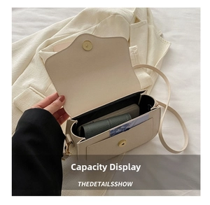 Detail of cream white leather saddle bag showing internal capacity and gold magnetic clasp