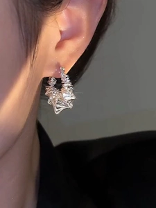 Close-up of silver hollow irregular circular earrings worn on a model for a luxury look
