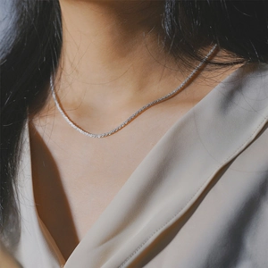 Collier ras du cou élégant en acier inoxydable argenté porté avec une chemise en satin chic